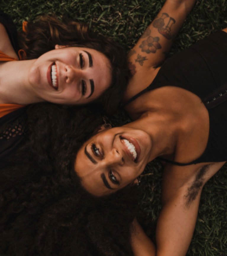 Two women lying on the grass, connecting and smiling